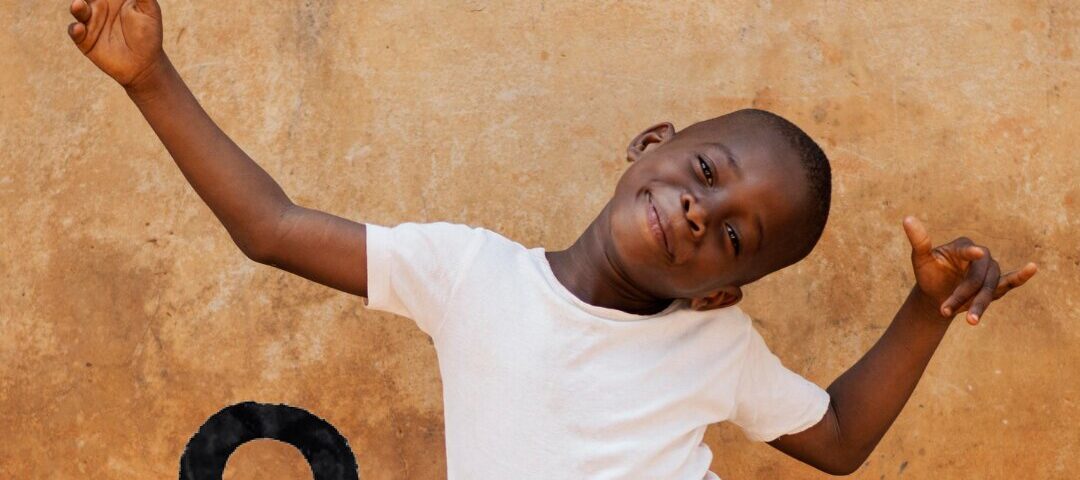 a boy sitting on the ground with his arms up | Primestars | What About the boys | International day of the boy child